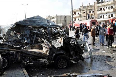 People look at damaged cars near the site of a twin bomb attack