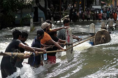 Flood-affected Sri Lankans struggle to cross a torrent of floodwaters in the outskirts of Colombo