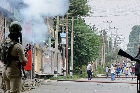 A Security person fires tear gas shell to disperse stone throwing youth