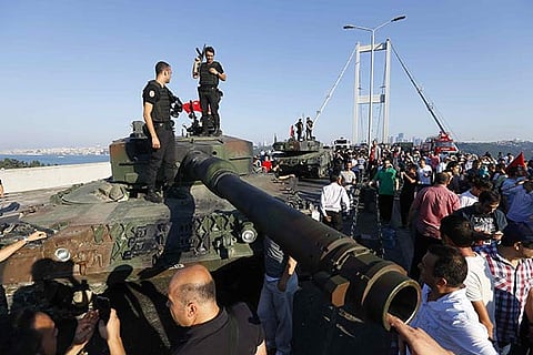 Policemen stand on a military vehicle after troops involved in the coup surrendered on the Bosphorus