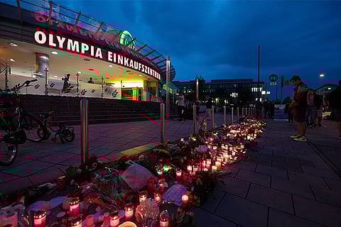 Candles and flowers lie in front of the Olympia-Einkaufszentrum shopping centre on July 23, 2016