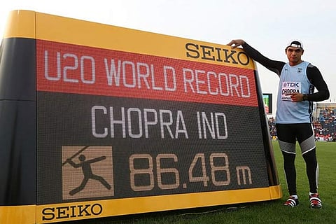 Neeraj Chopra poses next to a digital board after his record effort