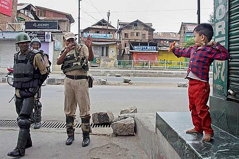 A boy plays with security jawans during curfew, in Downtown area of Srinagar