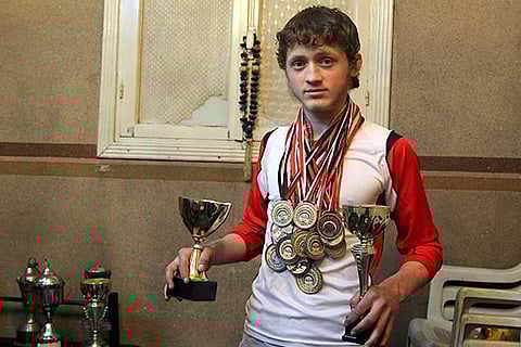 Gymnast Ahmad al-Sawas with his medals at home, in Syria