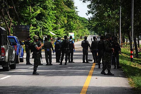 Thai soldiers watch as a forensic unit inspects the scene of an attack