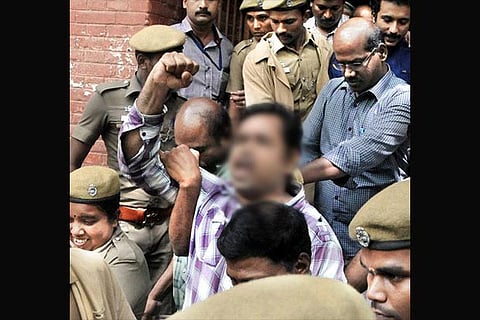 A file photo of a prisoner being escorted by many cops
