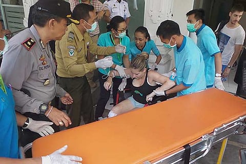 Workers assist a tourist injured in the explosion