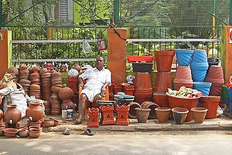 O Rajendran sits amidst his terracotta wares. His wife?s photo is displayed on the wall