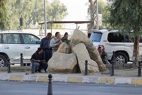 Peshmerga forces stand behind rocks at a site of an attack by Islamic State militants in Kirkuk