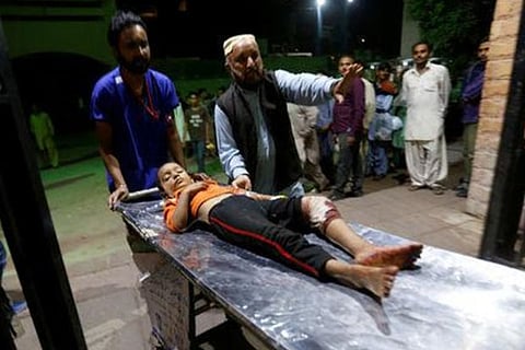 An injured boy is wheeled from the ambulance after an explosion in at the Shah Noorani Shrine