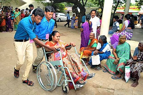 Volunteers help a differently-abled woman to cast her vote in Thanjavur