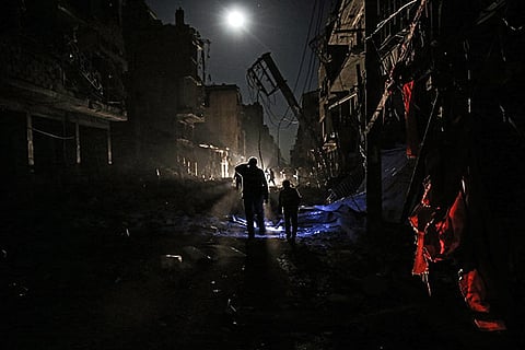 Syrians walk amid debris and destroyed buildings following a reported government airstrike