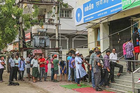People stand in queue outside an ATM in Chennai