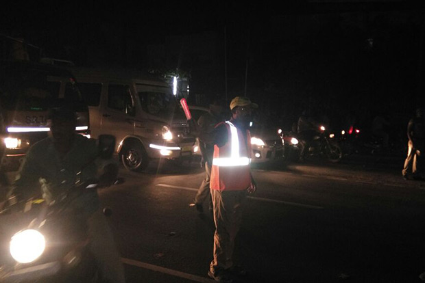 Picture shows one of the traffic volunteers helping police regulate traffic at night on NH45