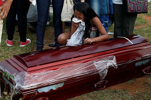 A woman cries beside her father's coffin in the cemetery