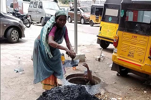 A woman and man at work in a manhole on a road in the city