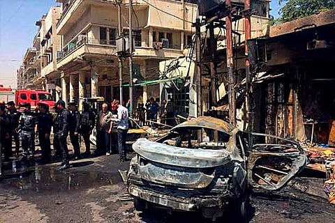 Iraqi security forces and civilians inspect the site of a deadly bomb attack, in Baghdad, Iraq