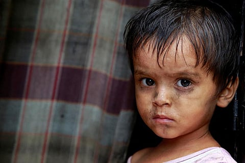A child from the Rohingya community stands outside a shack in a camp in Delhi