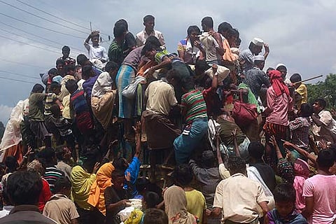 Rohingya refugees climb a truck to receive aid distributed by local organisations
