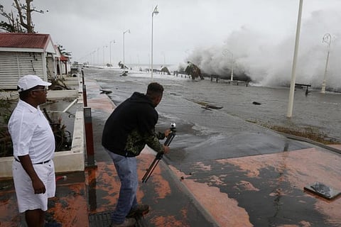 A man takes a video in a flooded seafront after the passage of Hurricane Maria