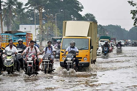 People move through a flooded road after heavy incessant rains lashed Chennai