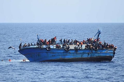 Migrants are seen on a capsizing boat before a rescue operation by Italian navy ships