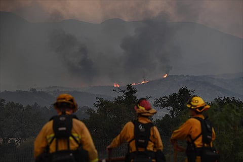 Firefighters keep watch while fire and smoke heads towards their area