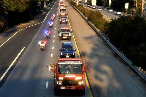 A procession carries the body of a fellow firefighter killed battling the Thomas wildfire