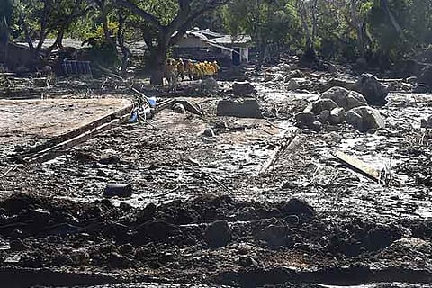 A search and rescue team make their way up a mud covered hillside in Montecito, California