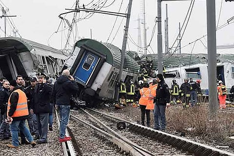 Rescue workers and police officers stand near derailed trains in Milan, Italy