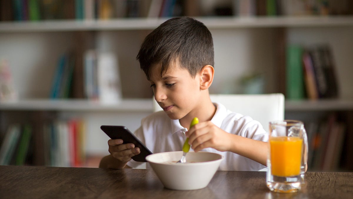 he is focused on a mobile phone while eating