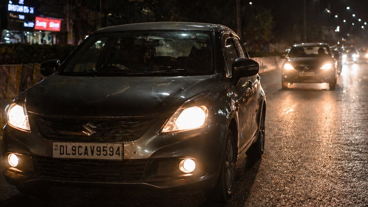 Headlights gleam on dark wet night road traffic
