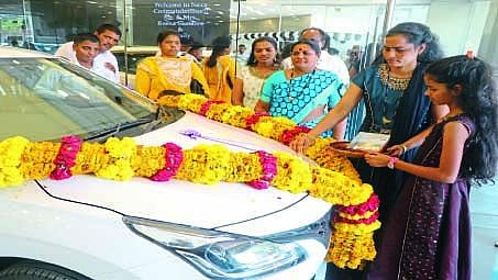 नवीन चारचाकी वाहन खरेदी केल्यावर वाहनाची पूजा करताना महिला.