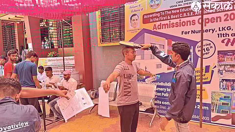An employee checks a student going for an exam through a metal detector at a center in the city.