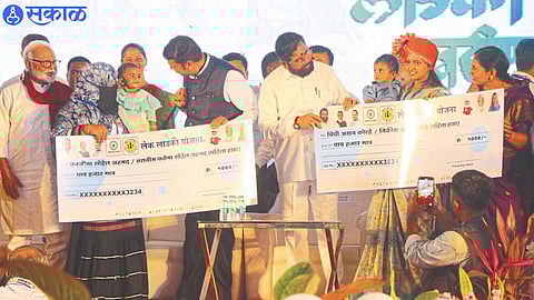 Chief Minister Eknath Shinde, Deputy Chief Minister Devendra Fadnavis while giving check to the beneficiaries of Lake Ladki Yojana in the grand camp organized under Women Empowerment Mission at Modi Maidan in Tapovan.