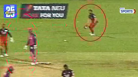 Suyash Sharma collects the ball with his cap 