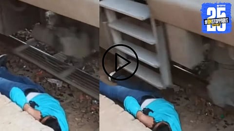 A Danger moment captured as a man lies motionless on the railway track while a train rushes over, leaving viewers in shock.


