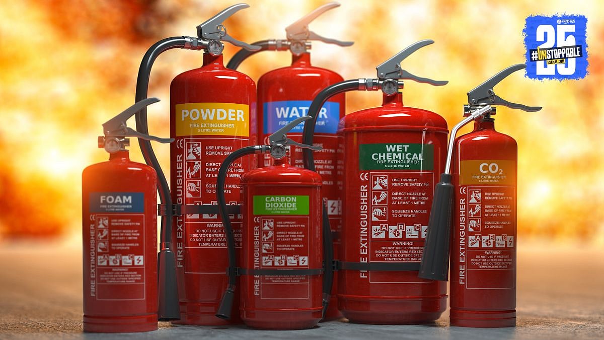 High-rise residential building with a red fire tender parked outside, firefighters inspecting equipment, and a "Fire Safety Notice" board visible on the society gate. High-rise residential building with a red fire tender parked outside, firefighters inspecting equipment, and a "Fire Safety Notice" board visible on the society gate.