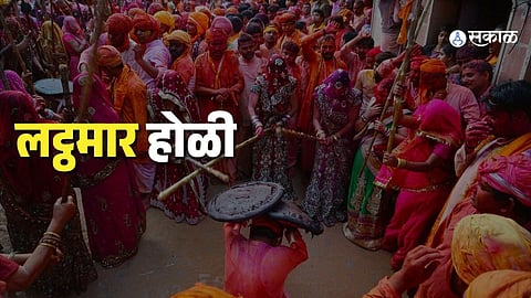 Women participate in a lively Lathmar Holi celebration as men dressed in sarees dance amid colorful festivities.