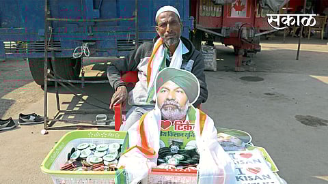 नवी दिल्ली - भारतीय किसान युनीयनचे नेते राकेश टिकैत यांचे पोस्टर तसेच बिल्ले विकणारा विक्रेता. (एएनआय)