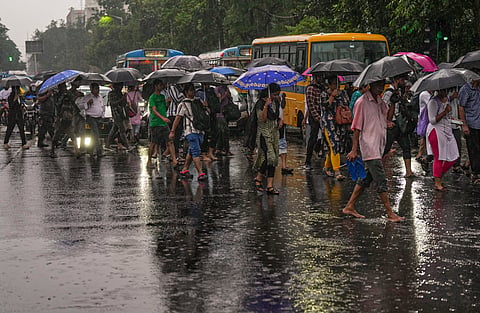 People cover themselves amid rainfall, in Kolkata, on Wednesday | PTI