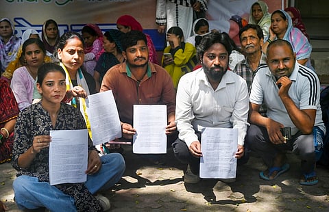 Residents from BR Camp, Masjid Camp, and DID Colony, gather outside the AICC headquarters holding documents to seek the intervention of Congress leader Rahul Gandhi, on Saturday | PTI