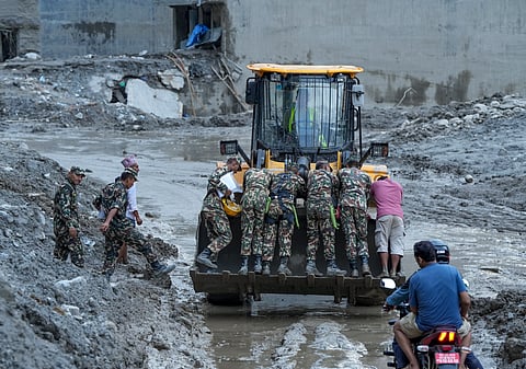 Security personnel stand on an excavator at a muddy area in the aftermath of flash floods, at Trishuli market, in Nuwakot district, on Sunday | PTI