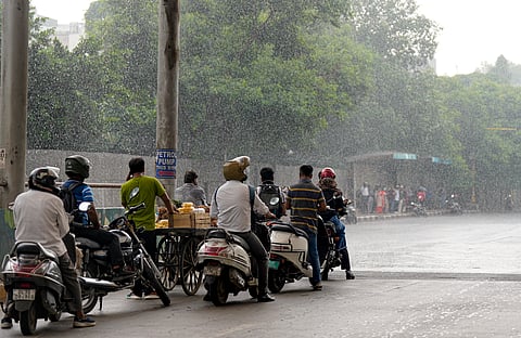 People take shelter under a foot over bridge amid rainfall, at Mathura Road, in New Delhi, on Wednesday | PTI