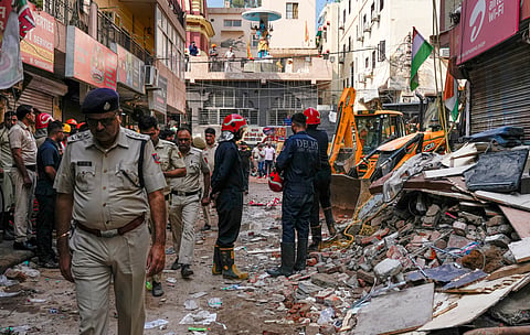 Rescue personnel stand near debris during a rescue operation on the second day after a 50-year-old five-storey building housing a boys' hostel collapsed, in Satya Niketan, on Monday | PTI