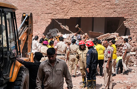 Police personnel, Delhi Fire Service officials, and Civil Defence volunteers coordinate debris clearing efforts, at Satya Niketan, on Monday | PTI