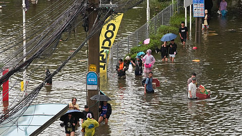 People wade through a flooded street after heavy rain in Bangkok, Thailand, on Sunday | PTI
