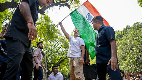 Rahul Gandhi waves the national flag while standing atop police barricades during a protest march, in New Delhi, on Tuesday | PTI