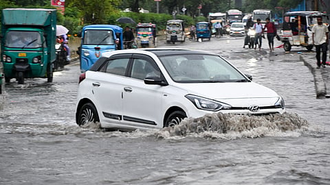 Commuters make their way through a waterlogged road after heavy rain, in Noida, on Monday | PTI