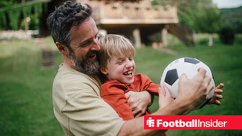 A father and son playing with a football